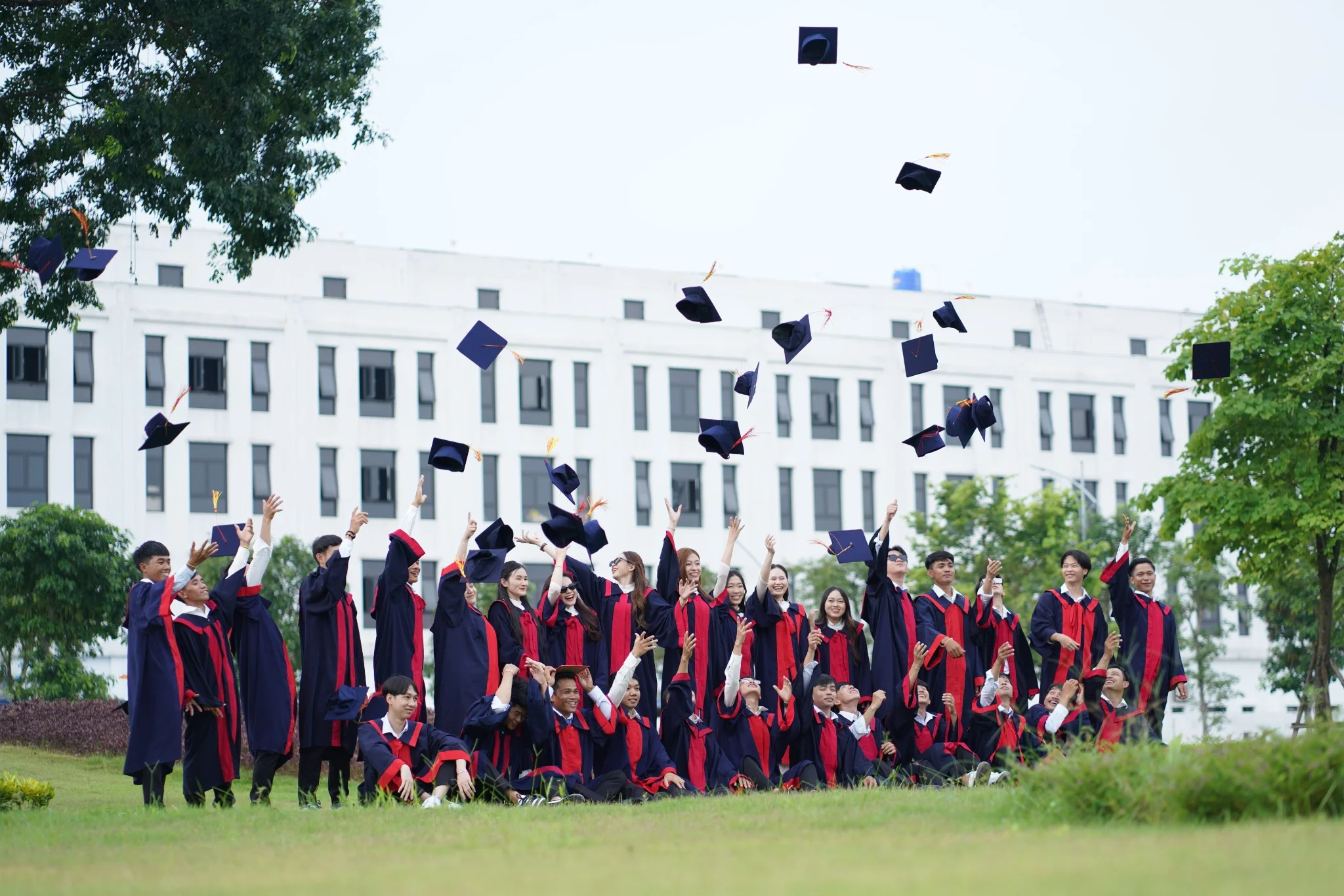 Groupe d'étudiants célébrant leur remise de diplôme en lançant leurs toques dans les airs.